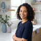 A friendly, diverse woman smiling in a bright, modern kitchen environment.
